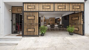 A modern entrance with a black metal gate, a concrete ramp, and a seating area with chairs and potted plants. - Piraeus Premium Suites (Piraeus)