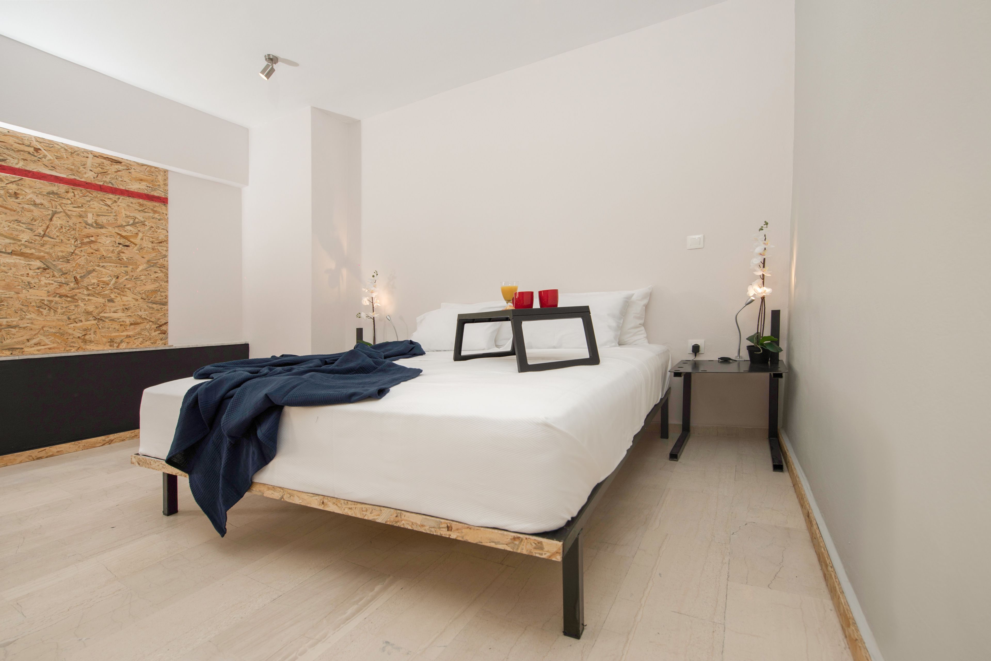 Une chambre moderne avec un cadre de lit en bois, une literie blanche et deux tables de chevet avec des lampes.