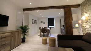 Un salon moderne avec une table à manger en bois, un canapé et un mur décoratif en pierre.