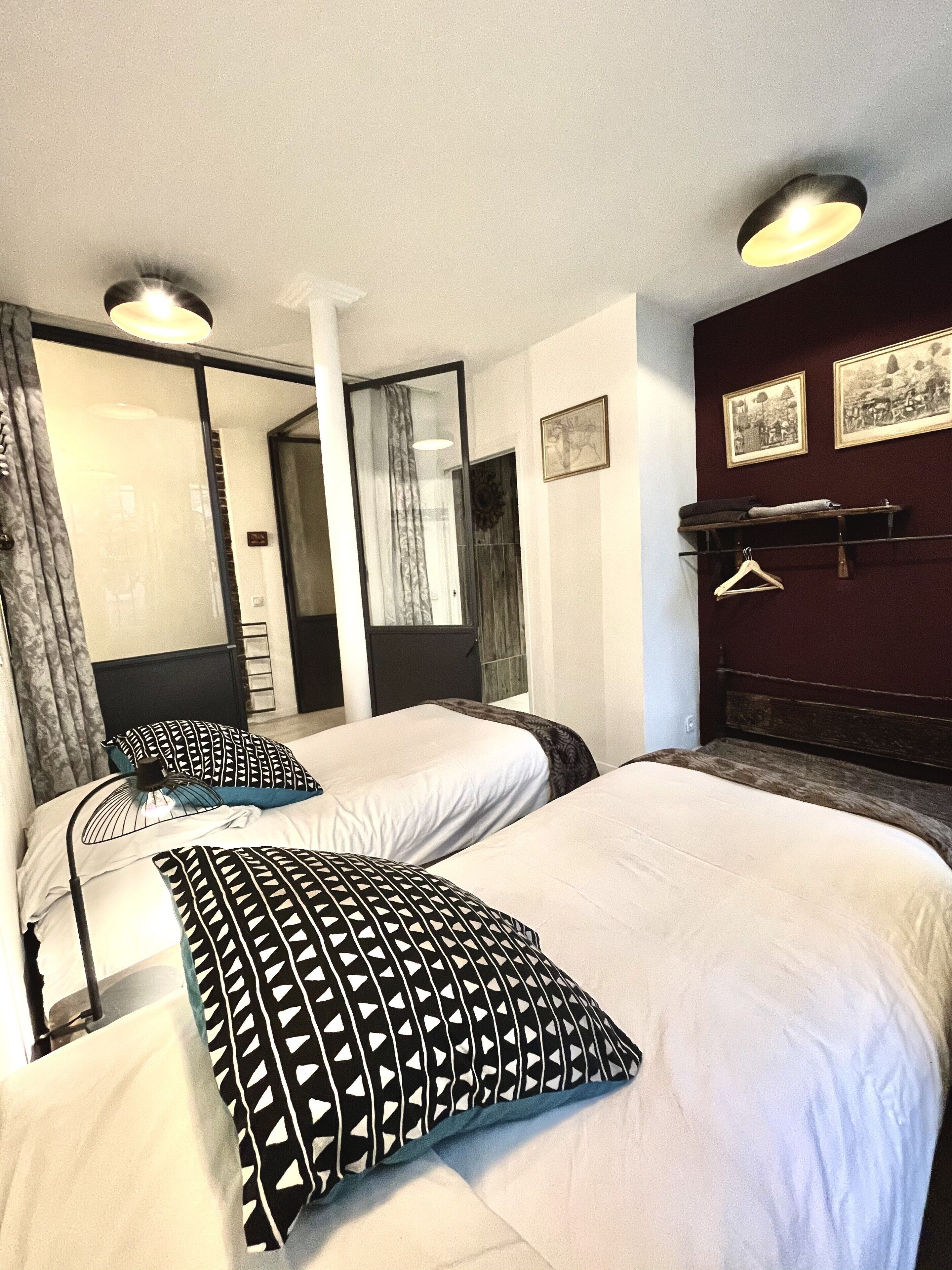 A hotel room with two beds, a large mirror, and a dark wooden headboard.