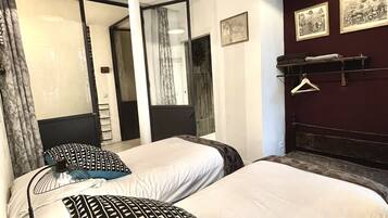 A hotel room with two beds, a large mirror, and a dark wooden headboard.