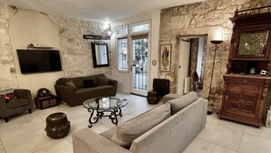 Un salon avec un mur en pierre, un canapé, une table basse et un téléviseur.
