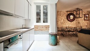 Une cuisine moderne avec des meubles blancs, une grande fenêtre et un mur en pierre.