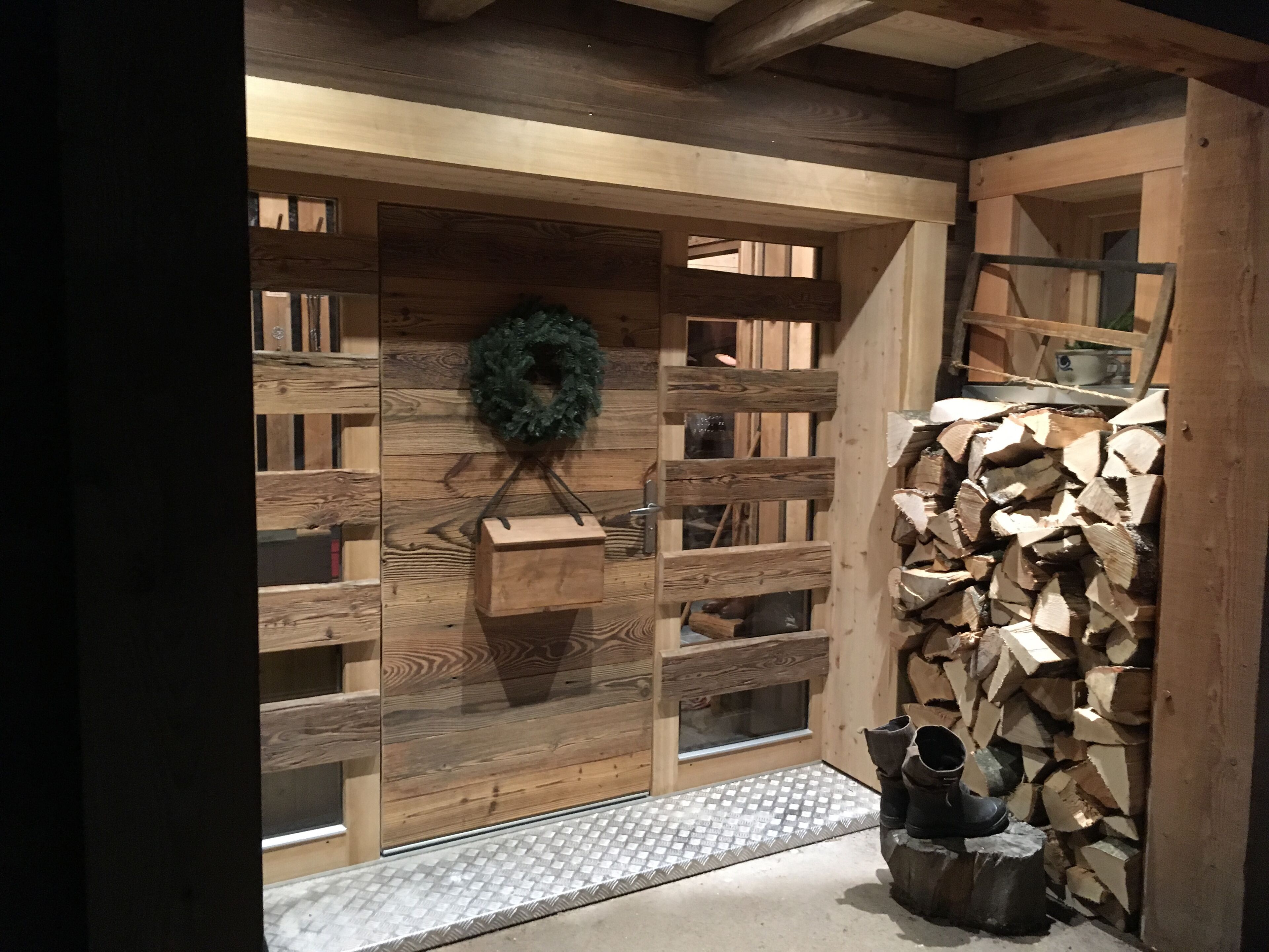 Ein Holzinnenraum mit Kamin, einem Kranz an der Wand und einem Holzstoß.