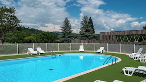 Une piscine entourée de chaises longues blanches et d’une clôture en bois.