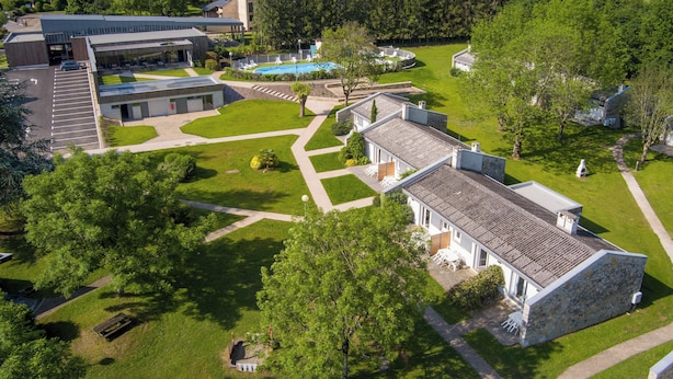 Vue aérienne d’un campus comprenant une piscine, plusieurs bâtiments et de vastes pelouses bien entretenues.