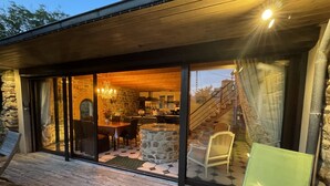 A modern house with a stone exterior, a wooden deck, and a glass-enclosed dining area with a stone table and chairs. - BRITTANY FINISTERE CROZON PENTY SPACIOUS AND LUMINOUS (Crozon)