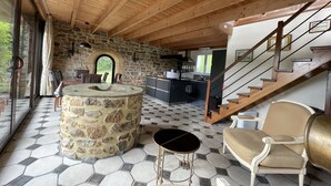A spacious living area with a stone fireplace, a round table, and a staircase leading to an upper level. - BRITTANY FINISTERE CROZON PENTY SPACIOUS AND LUMINOUS (Crozon)
