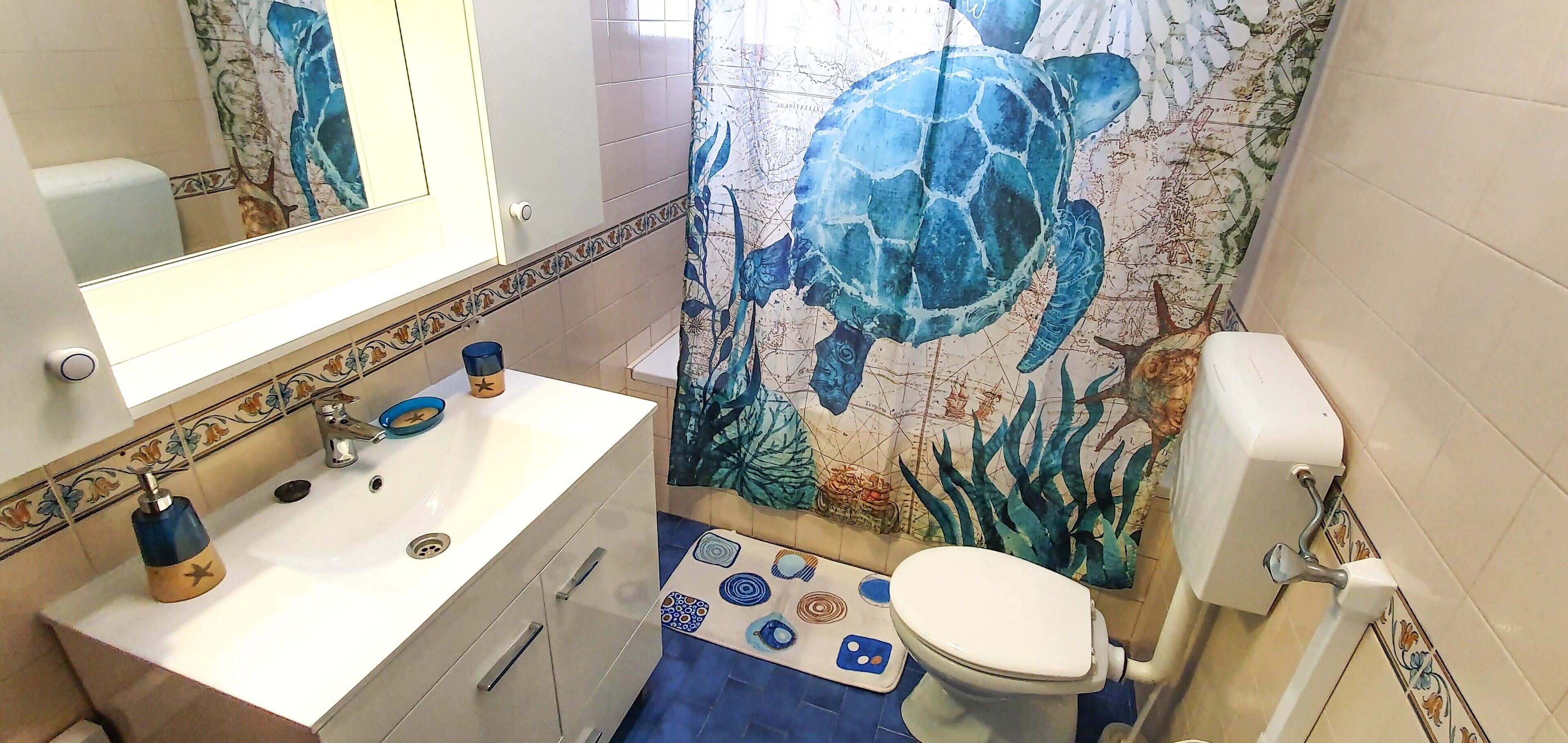 A bathroom with a white sink, blue faucet, and a toilet.