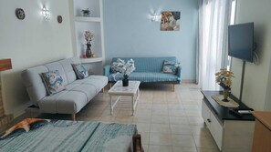 A living room with a sofa, a coffee table, and a TV.