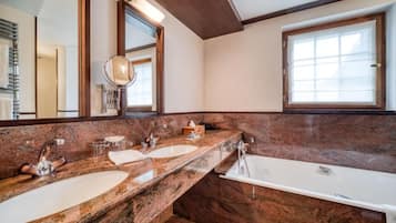 A bathroom with two sinks, a bathtub, and a large mirror.