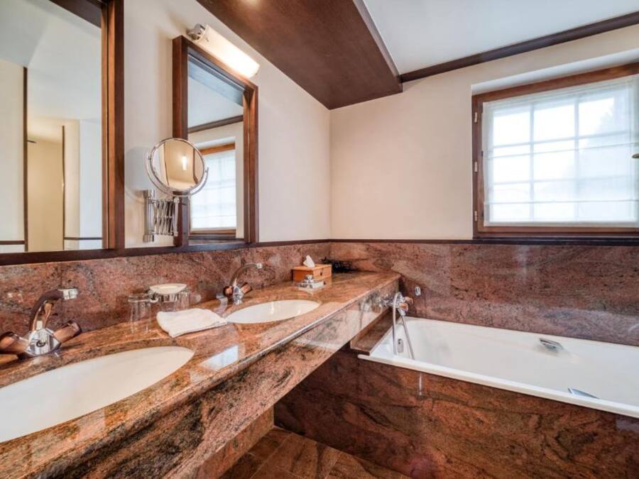 A bathroom with two sinks, a bathtub, and a large mirror.