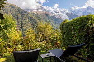 Vista de un paisaje montañoso con una silla y una mesa en primer plano.