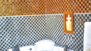 Un baño con una bañera grande, paredes de mosaico y un cuadro en la pared.