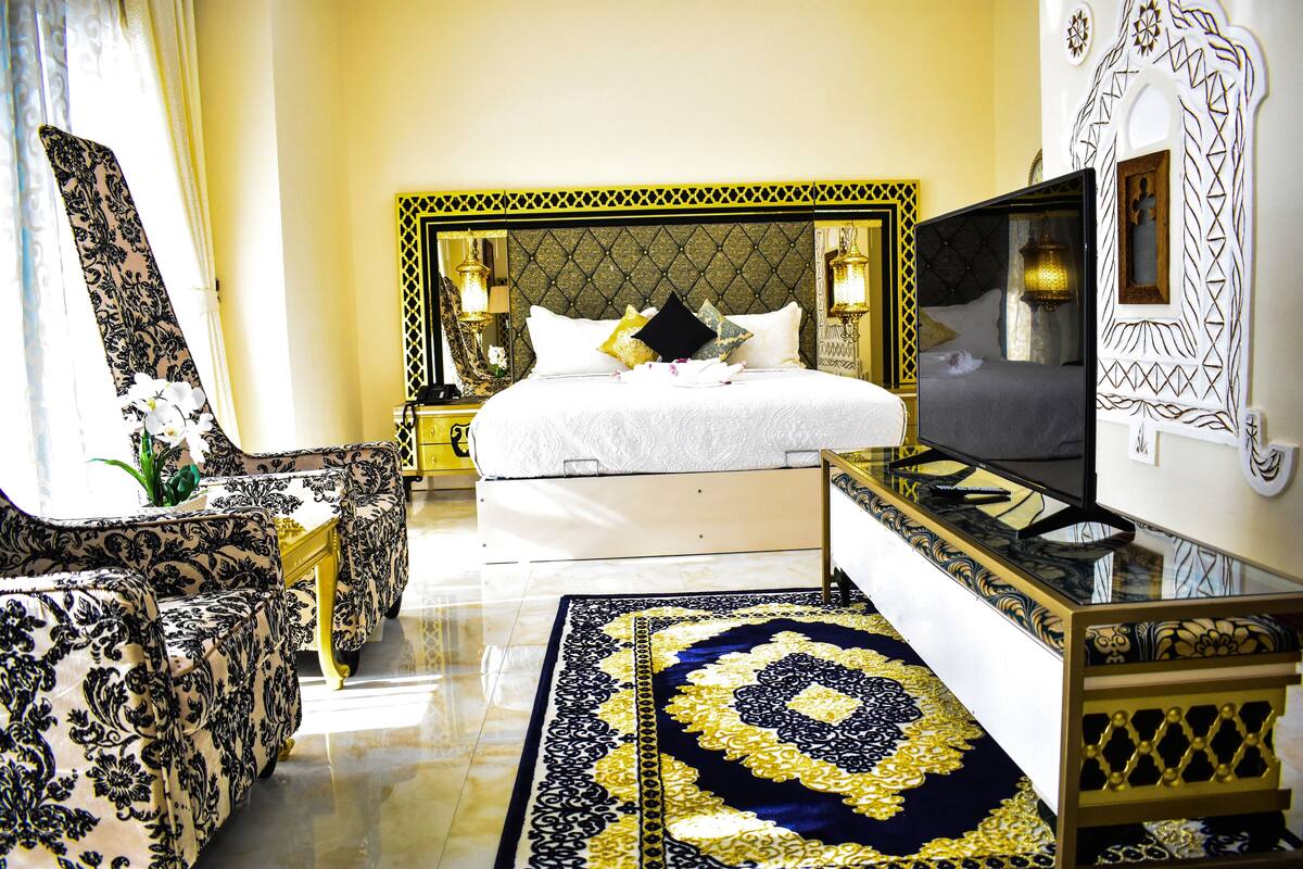 Une chambre d’hôtel avec un lit, une télévision, un canapé et un tapis décoratif.