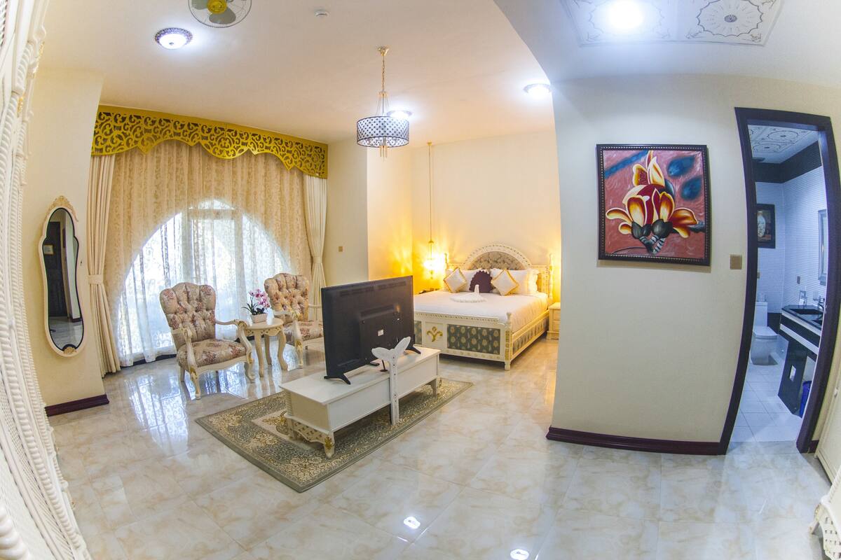 Une chambre d’hôtel avec un lit, une télévision, une chaise, une table et un tableau au mur.