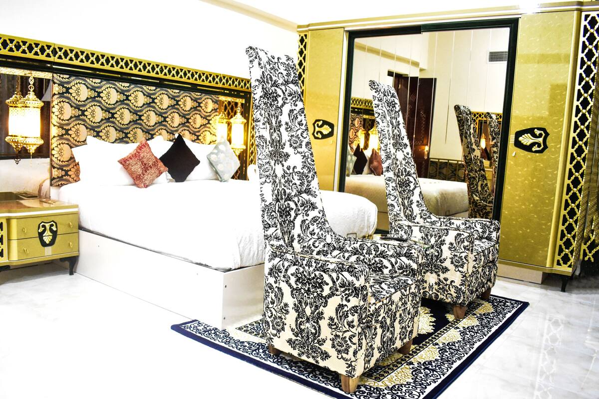 Une chambre à coucher avec un lit, des tables de chevet, un miroir et une chaise à motifs.