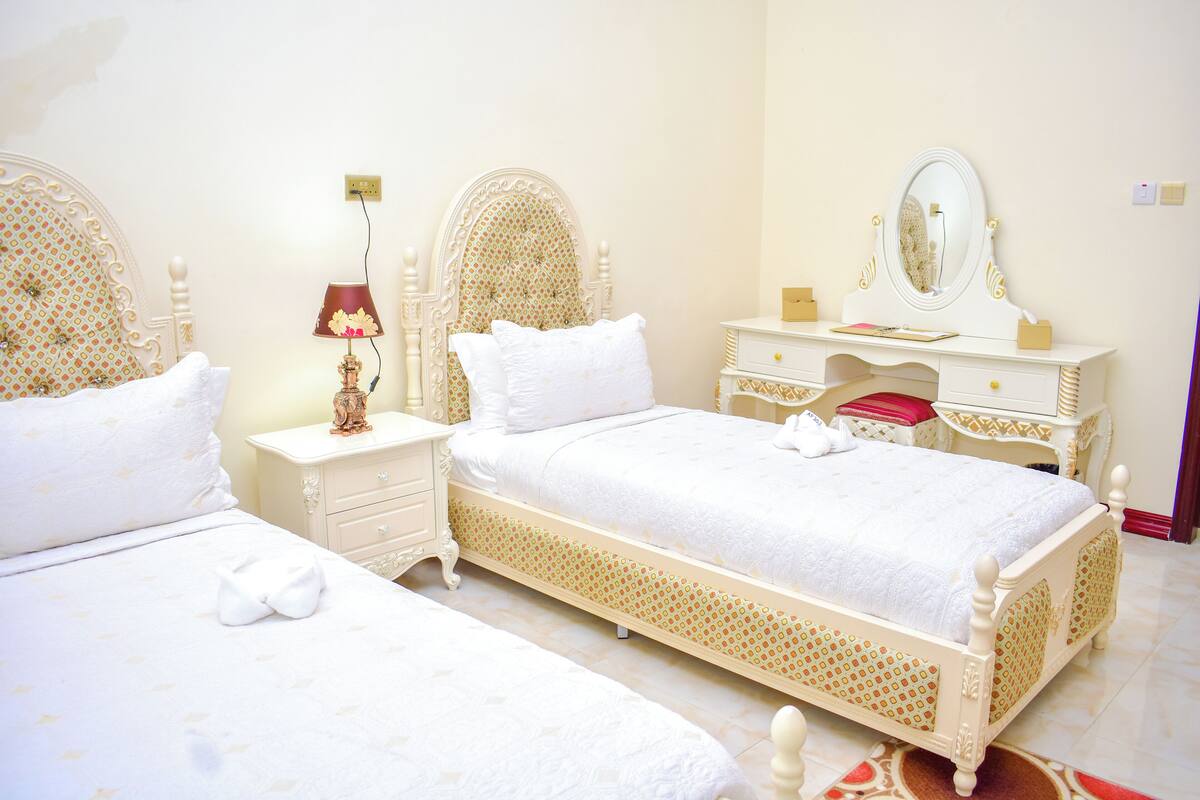 Une chambre avec deux lits, une commode, un miroir et une lampe.