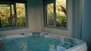 Ein Spa-Raum mit Whirlpool, zwei Fenstern und Blick auf Grünfläche.