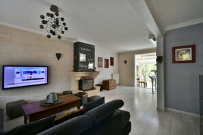 A modern living room with a flat-screen TV, a fireplace, and a dining area.