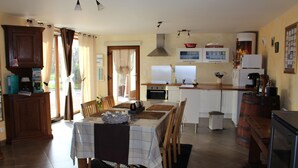 Uma cozinha com mesa de jantar, cadeiras, fogão, forno e geladeira.