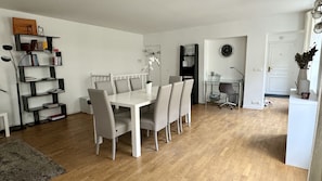 A modern, well-lit dining area with a white table and chairs, surrounded by bookshelves and a small office space.