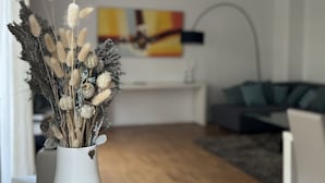 Moderni olohuone, jossa on puupöydällä valkoinen maljakko, jossa on kuivattuja kasveja.