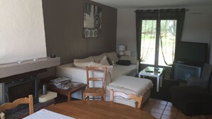 A cozy room with a fireplace, a sofa, a TV, and a dining table. - Charming cottage with private pool in Black Périgord  (Le Bugue)