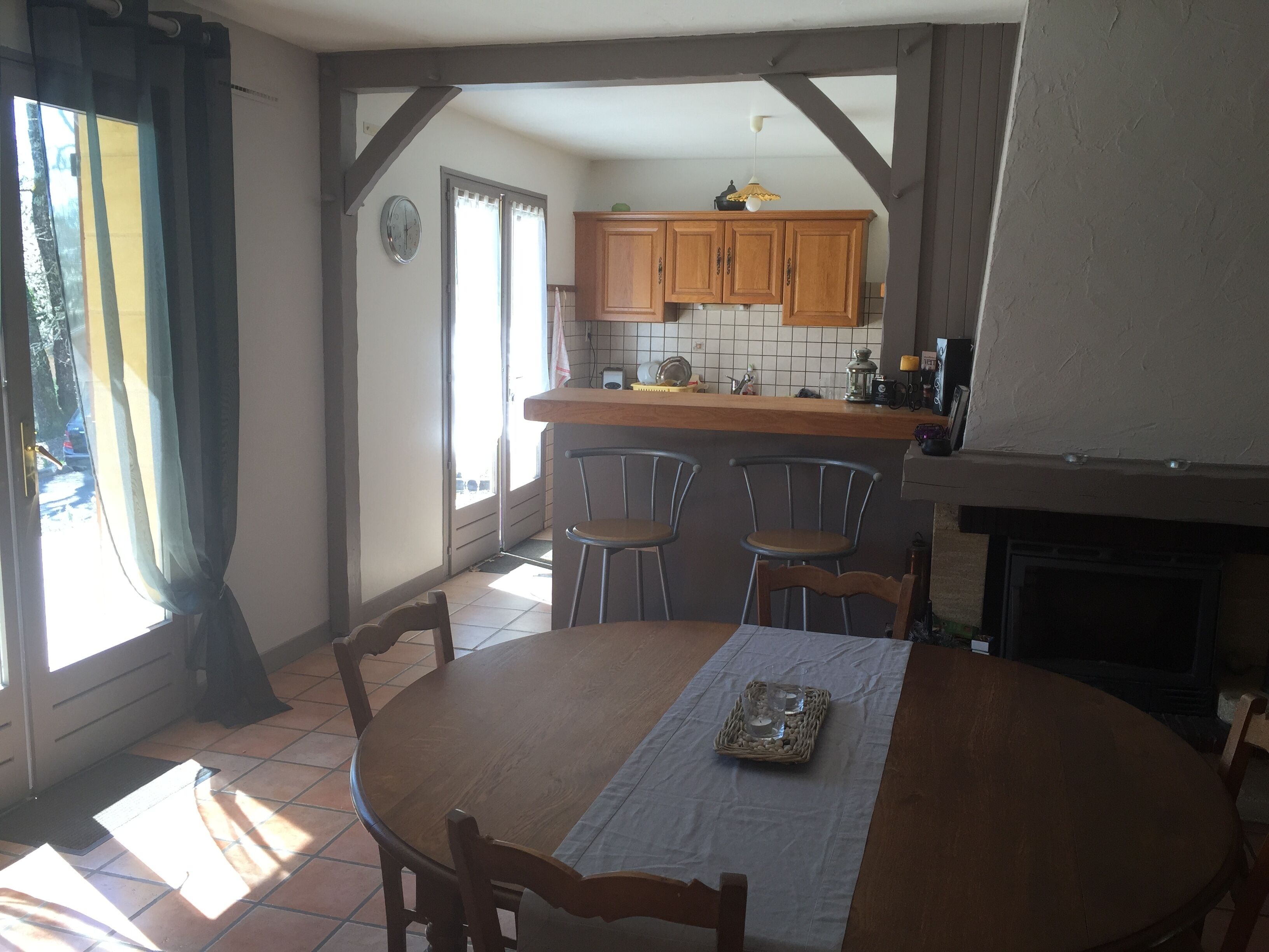 A dining area with a round wooden table, two chairs, and a small square table with a tray.