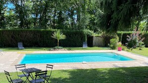A rectangular swimming pool with a tiled deck, surrounded by a well-maintained lawn and various plants. - Charming cottage with private pool in Black Périgord  (Le Bugue)