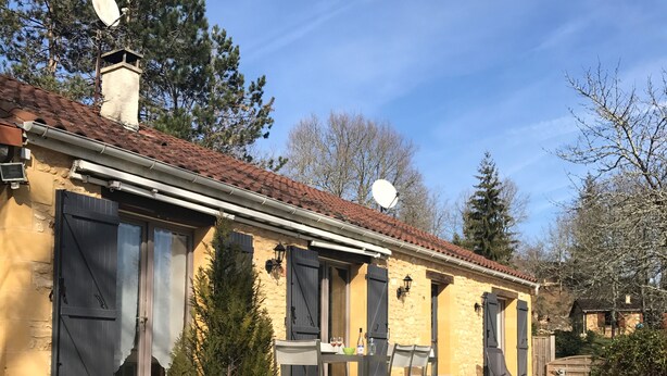 A two-story building with a tiled roof, satellite dishes, and a small outdoor seating area with a table and chairs. - Charming cottage with private pool in Black Périgord  (Le Bugue)