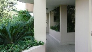 A corridor with a tiled floor, white walls, and a planter with green plants. - Charming, sunny, comfortable, 2 rooms Antibes, very close to the sea ON FOOT (Antibes)