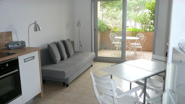 A compact living space with a kitchenette, a sofa, a dining table, and a sliding glass door leading to an outdoor patio area. - Charming, sunny, comfortable, 2 rooms Antibes, very close to the sea ON FOOT (Antibes)