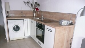 A compact kitchen with a washing machine, oven, and sink. - Charming, sunny, comfortable, 2 rooms Antibes, very close to the sea ON FOOT (Antibes)