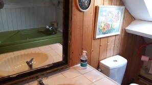 Bathroom features a bathtub, toilet, and sink area with a framed painting.