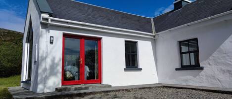 Una casa moderna con fachada blanca, puerta roja y techo gris.
