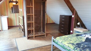 Un dormitorio con un armario de madera, una cama, un tocador y un escritorio con una lámpara.