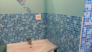 Un baño con lavamanos, espejo y azulejos de mosaico azules.