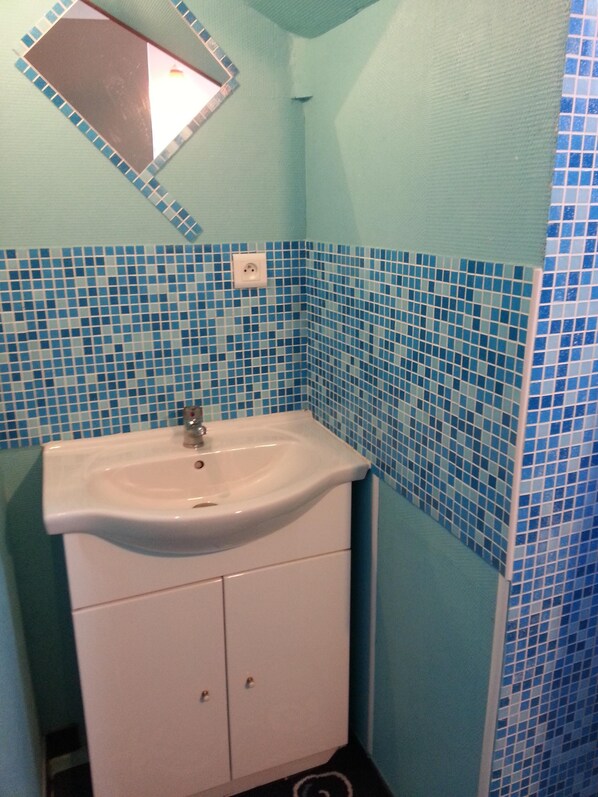 Une salle de bain avec un lavabo, un miroir et des carreaux de mosaïque bleus.