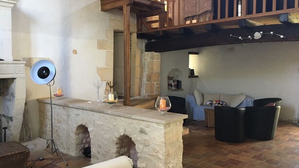A rustic interior with a stone fireplace, a wooden staircase, and a cozy seating area with a sofa and armchairs. - SAINT-SORNIN Atypical house with large plot 900 m2 closed ripe (Saint-Sornin)