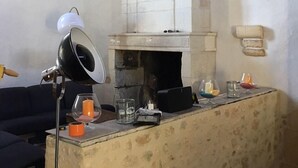 A rustic interior with a stone fireplace, a modern lamp, and a small bar area with glasses and candles. - SAINT-SORNIN Atypical house with large plot 900 m2 closed ripe (Saint-Sornin)