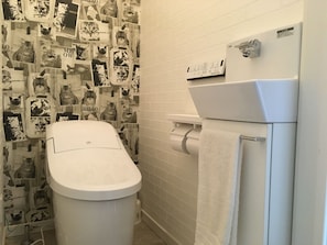 A bathroom with a toilet, a paper towel dispenser, and a towel rack. - Guest House Ori Ori (Niigata)