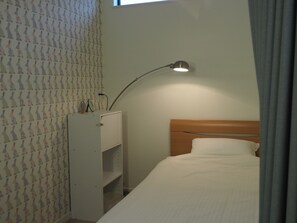 A bedroom with a bed, a nightstand, a desk, and a lamp. - Guest House Ori Ori (Niigata)