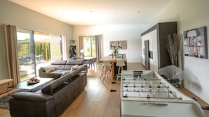 Ein modernes Wohnzimmer mit einer Couch, einem Kicker und einem Essbereich mit Tisch und Stühlen.