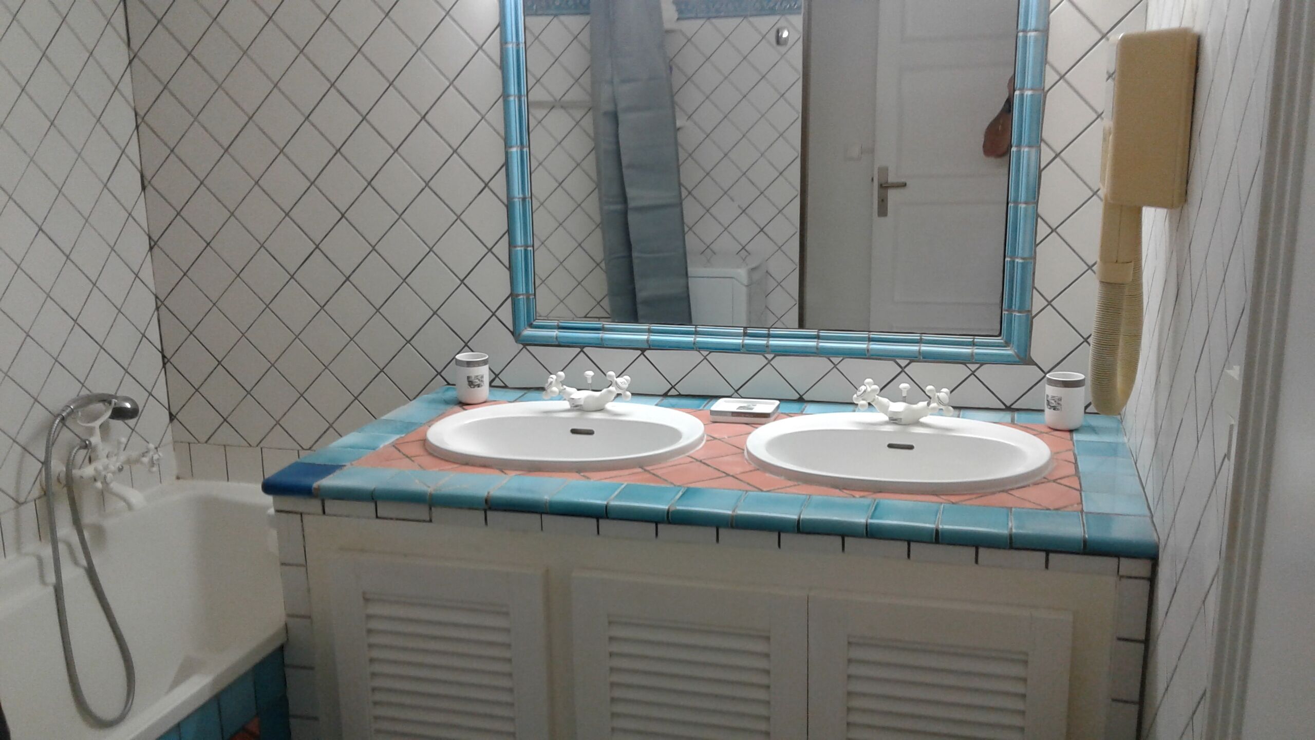 Une salle de bain avec deux lavabos, un miroir et une baignoire.