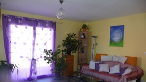 Una sala de estar con un sofá, una mesa de centro, una estantería y una planta en maceta.