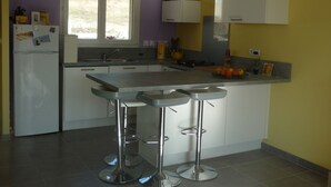 Una cocina moderna con una isla central, taburetes de bar, un refrigerador y una ventana.