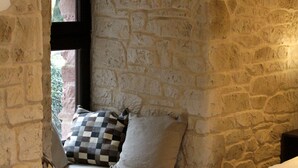 A stone-walled room with a window, a bed, and a checkered pillow. - Logis/Jacuzzi Studio **** La chute 40m² from 1 to 2 pers freiburg, basel, colmar  (Baldersheim)