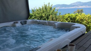 Ein Whirlpool mit einer Platte Croissants und Kaffee, mit Blick auf eine malerische Landschaft.