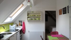 A compact kitchen with a skylight, white cabinets, a radiator, and a dining area with a table and chairs. - A Cocoon for 2 People With a Beautiful View of the Valley Tournai (Beclers)